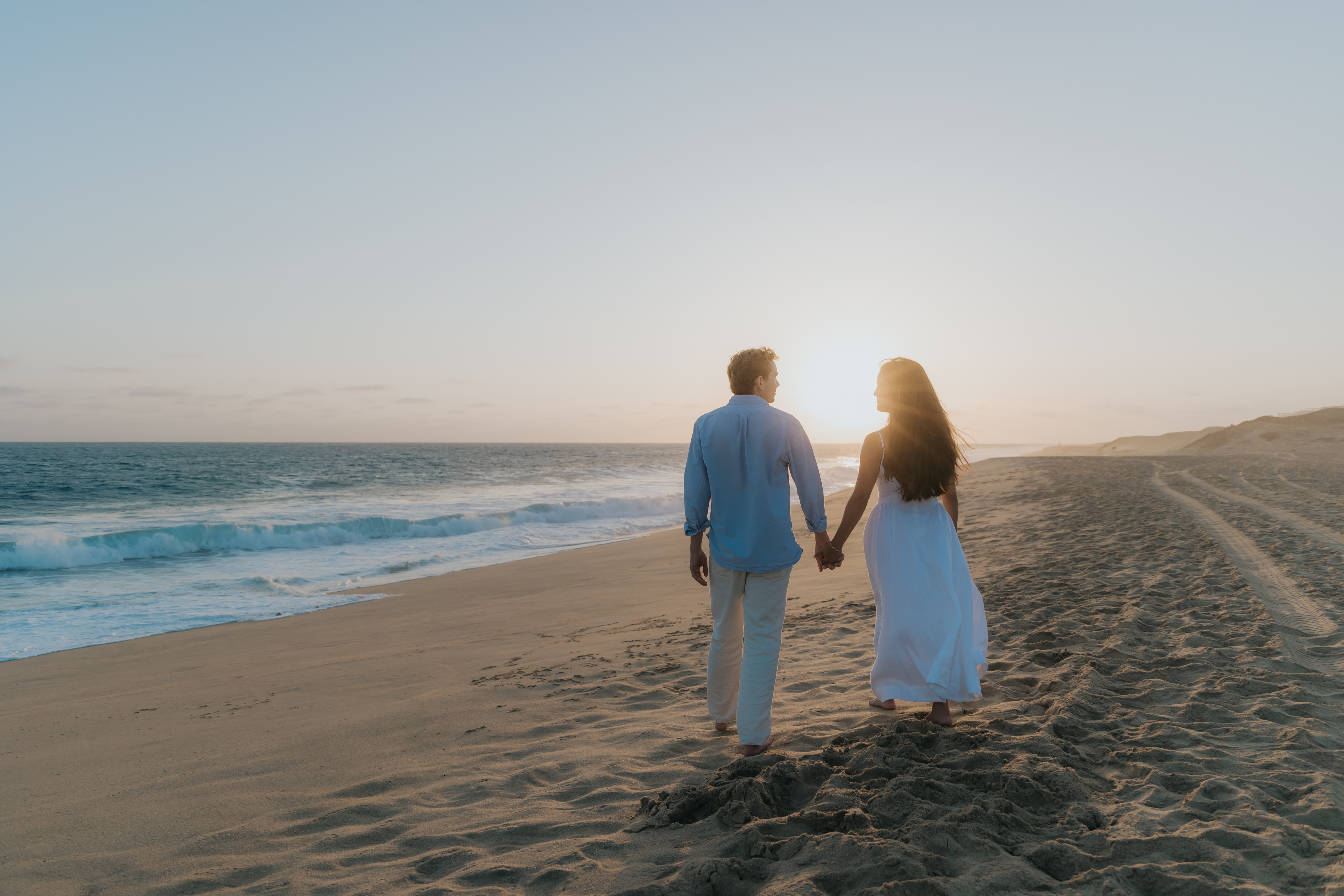 Allie and Jeremy walking along the beach at sunset